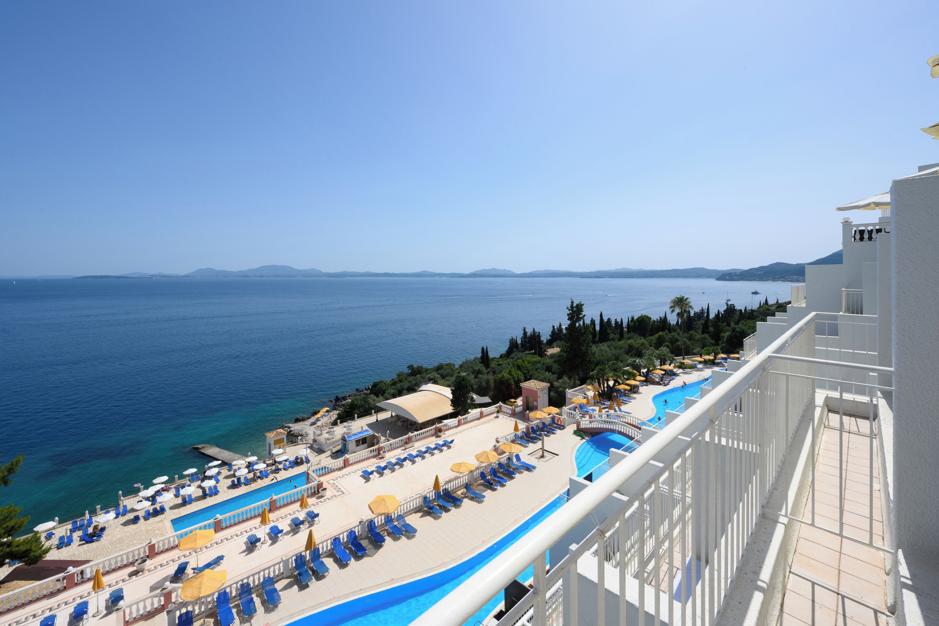 A resort with a pool area, lounge chairs, and a view of the sea.