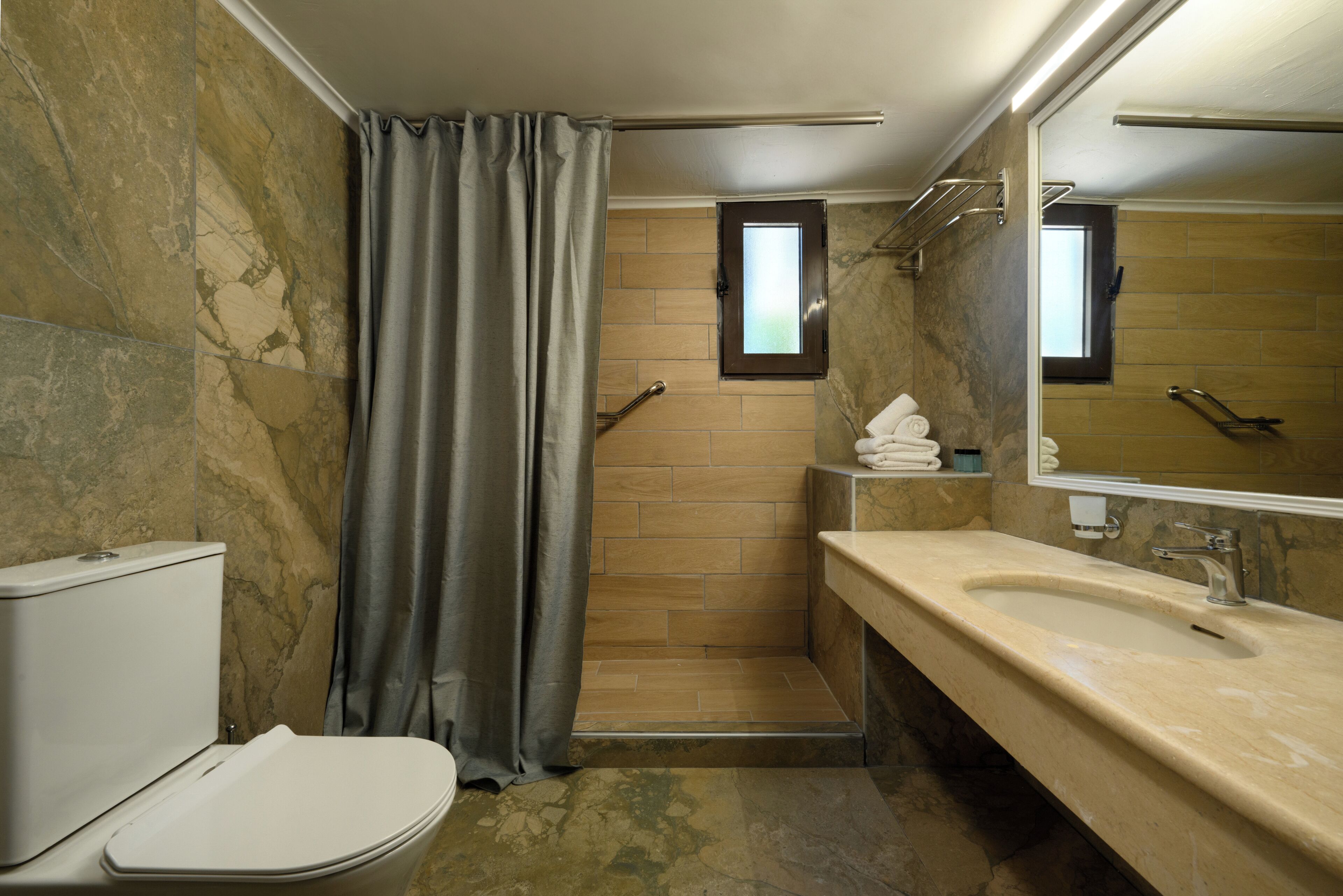 A bathroom with a toilet, shower, and sink.