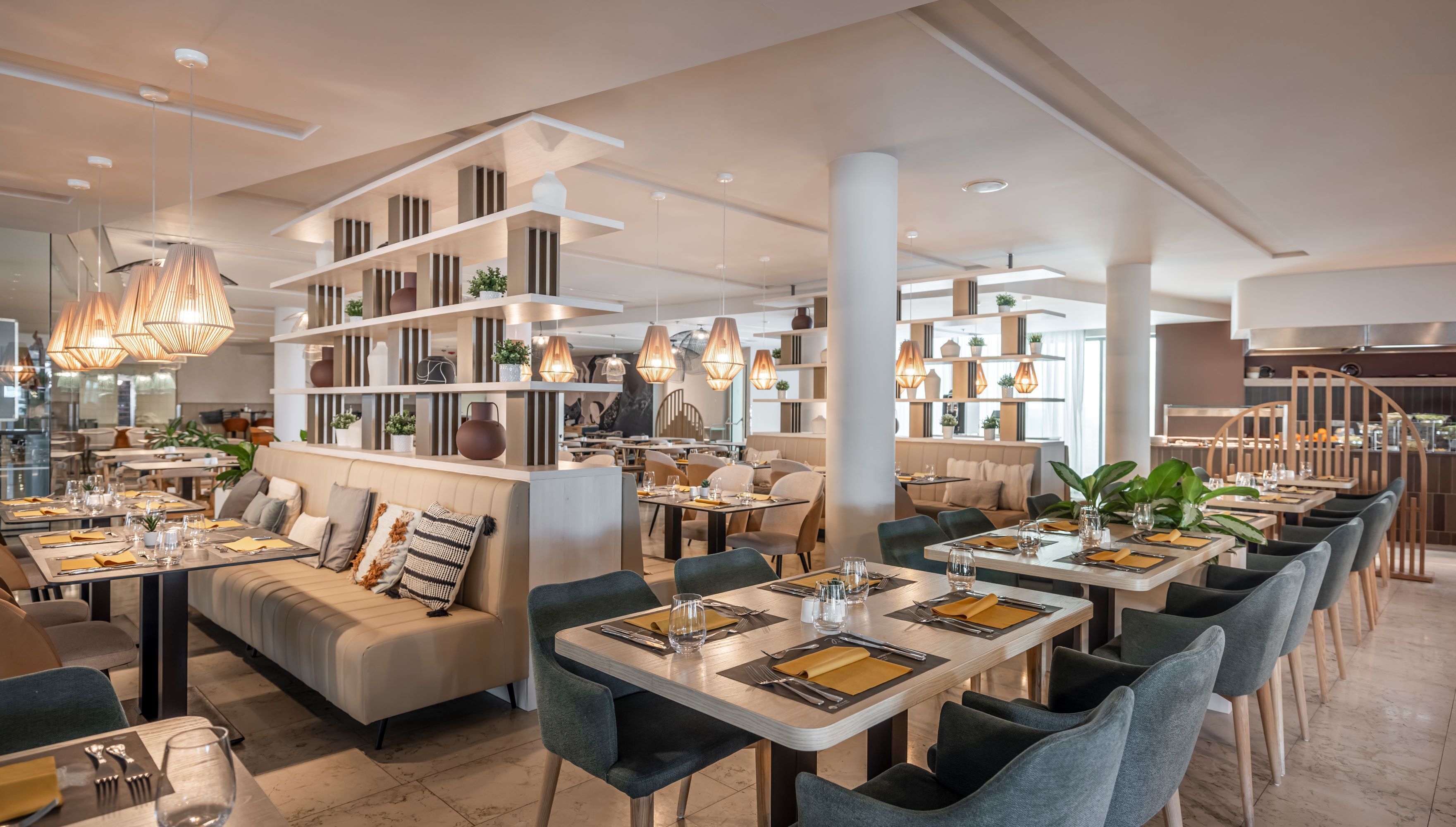 A modern restaurant interior with high tables, comfortable seating, and decorative lighting.