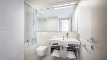 A modern bathroom with a glass shower enclosure, a white toilet, a white sink with a mirror above it, and a towel rack.