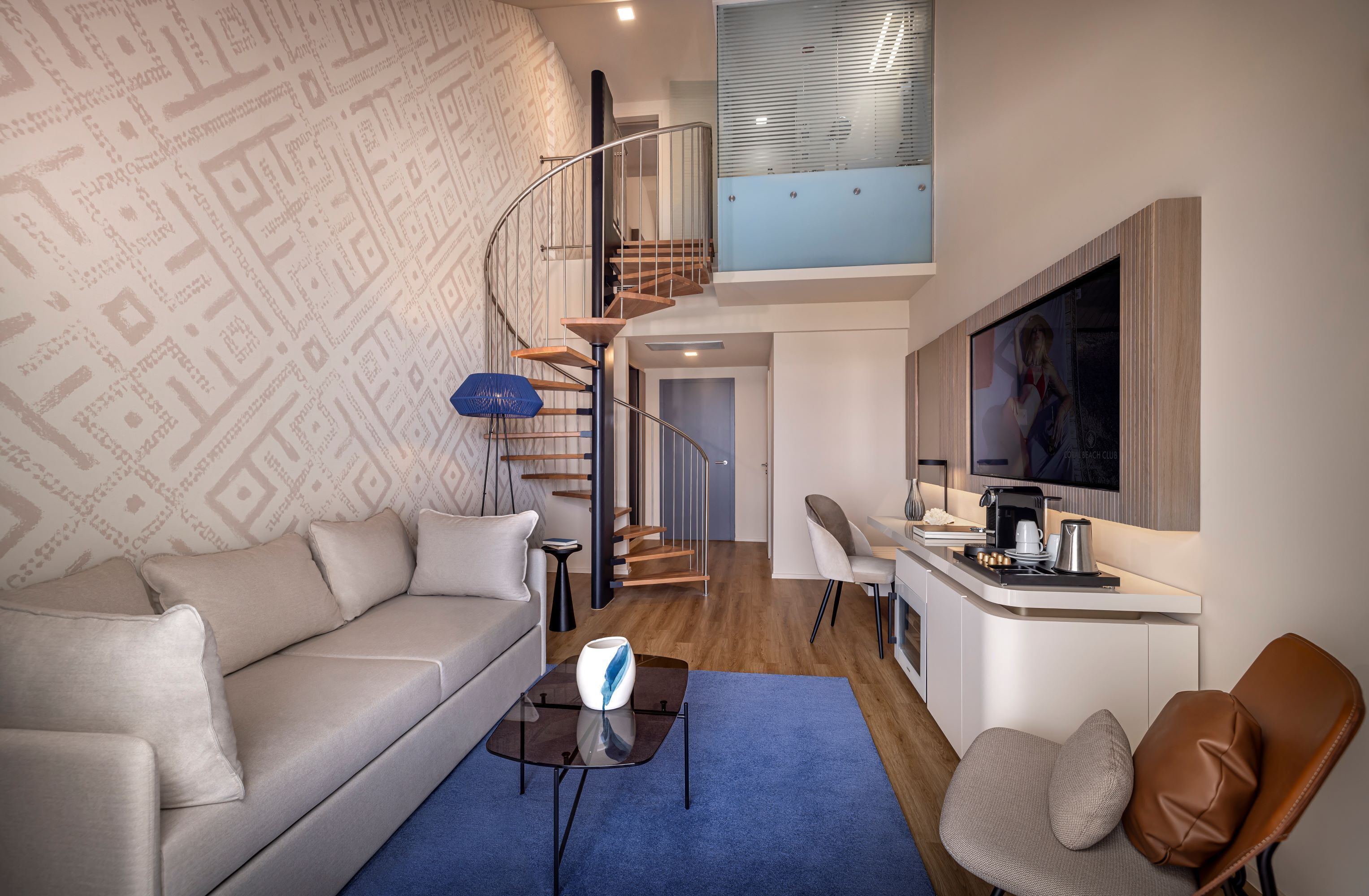 A modern living room with a sofa, coffee table, and a TV mounted on the wall.