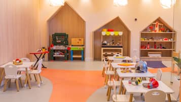 Uma sala de brinquedos infantis com mesas, cadeiras e brinquedos educativos.