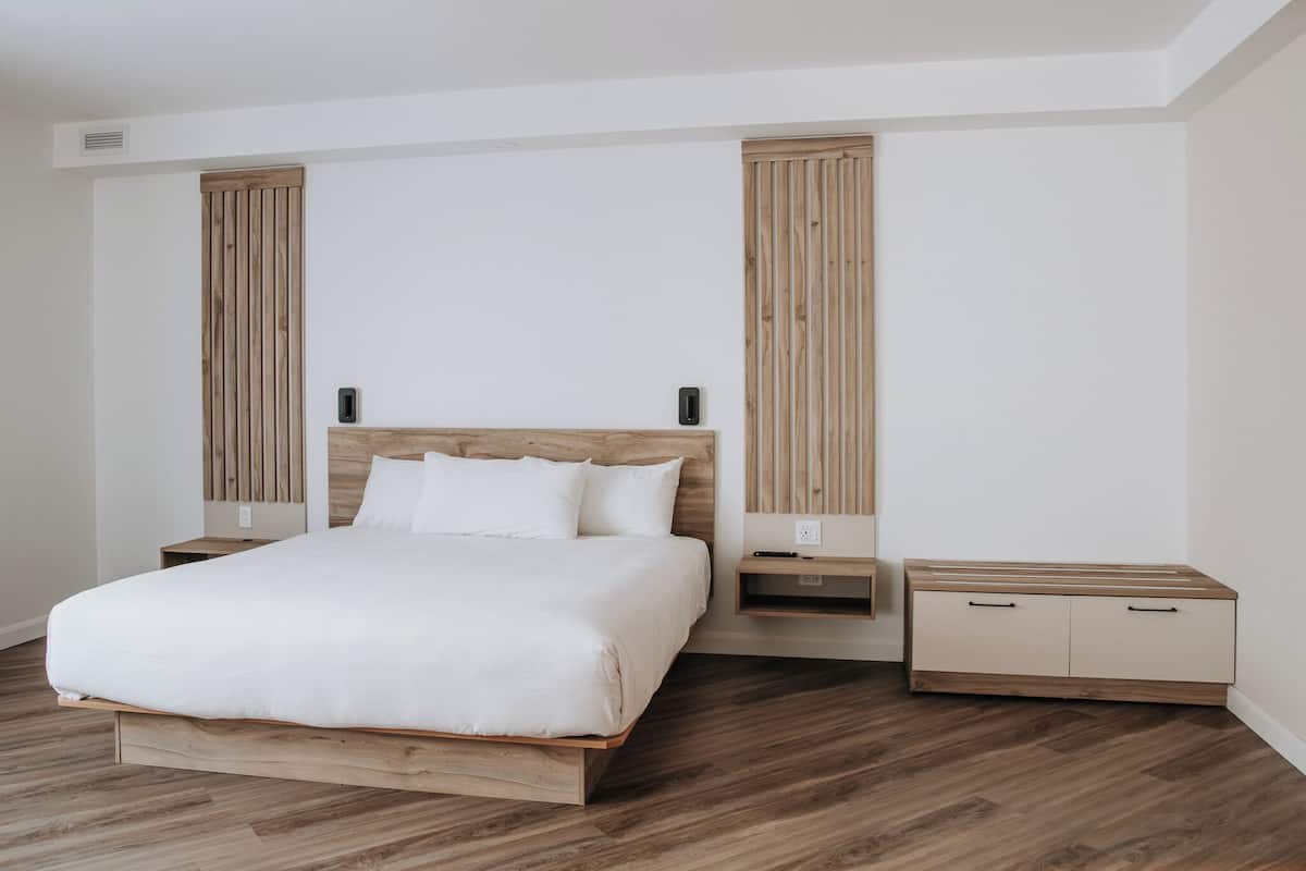 Un dormitorio moderno con una cama de madera, mesitas de noche y un armario empotrado.