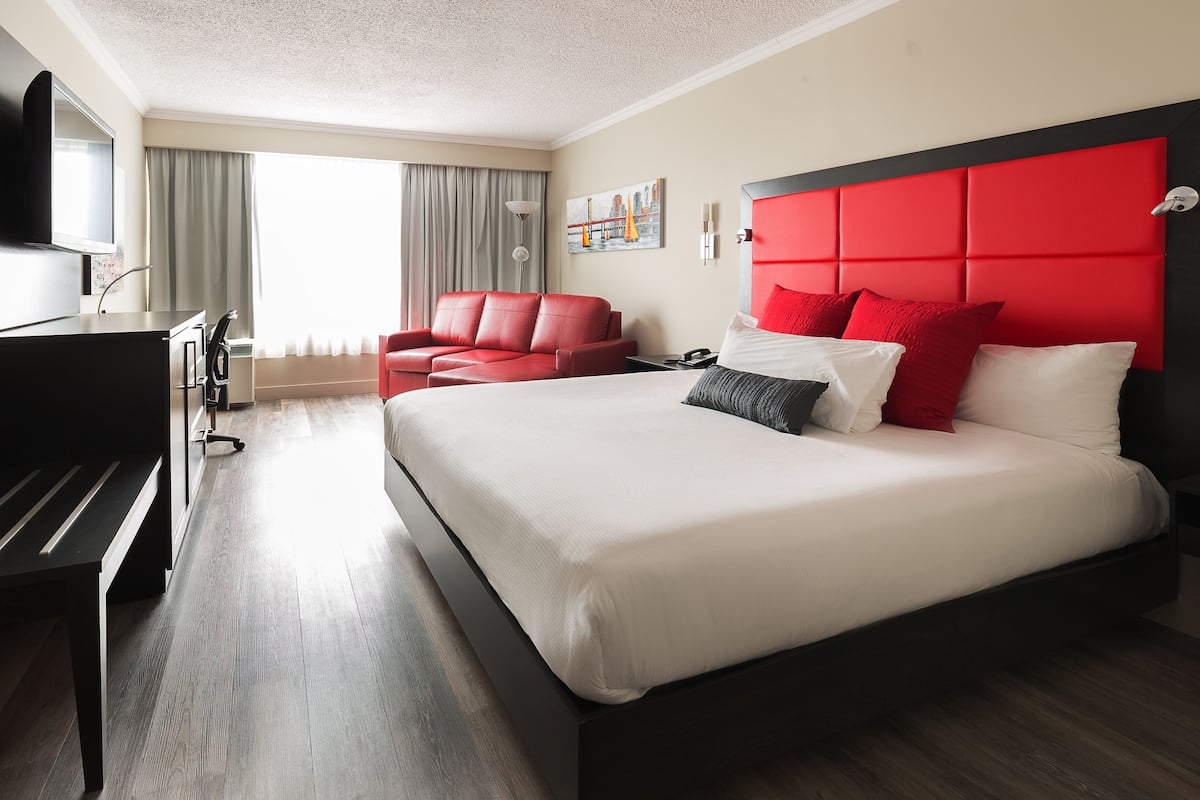 Habitación de hotel con cama, escritorio, silla y televisión.