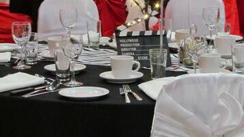 Una mesa de banquete dispuesta con manteles blancos y rojos, platos, copas y cubiertos.