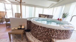 Un área de hidromasaje con paredes de mosaico, muebles de mimbre y una vela sobre una mesa.
