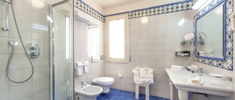A bathroom with a shower, toilet, bidet, and sink.