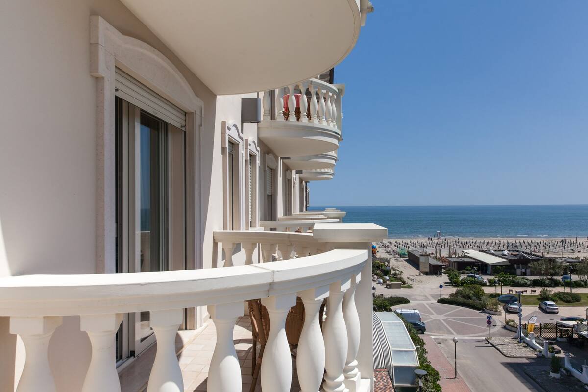 A balcony with white balustrades overlooking a beach.