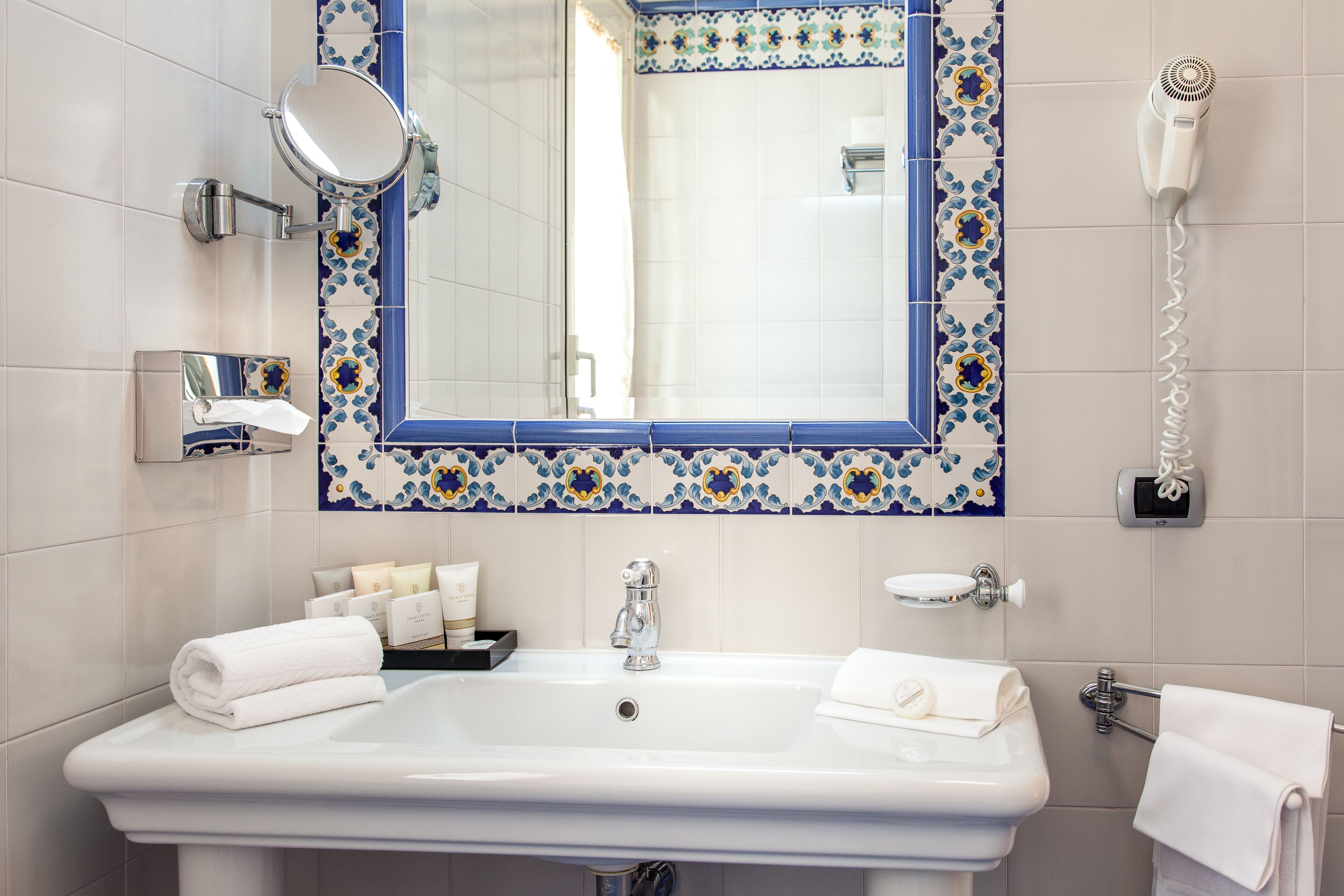 A bathroom with a white sink, a mirror, a hairdryer, and a towel rack.
