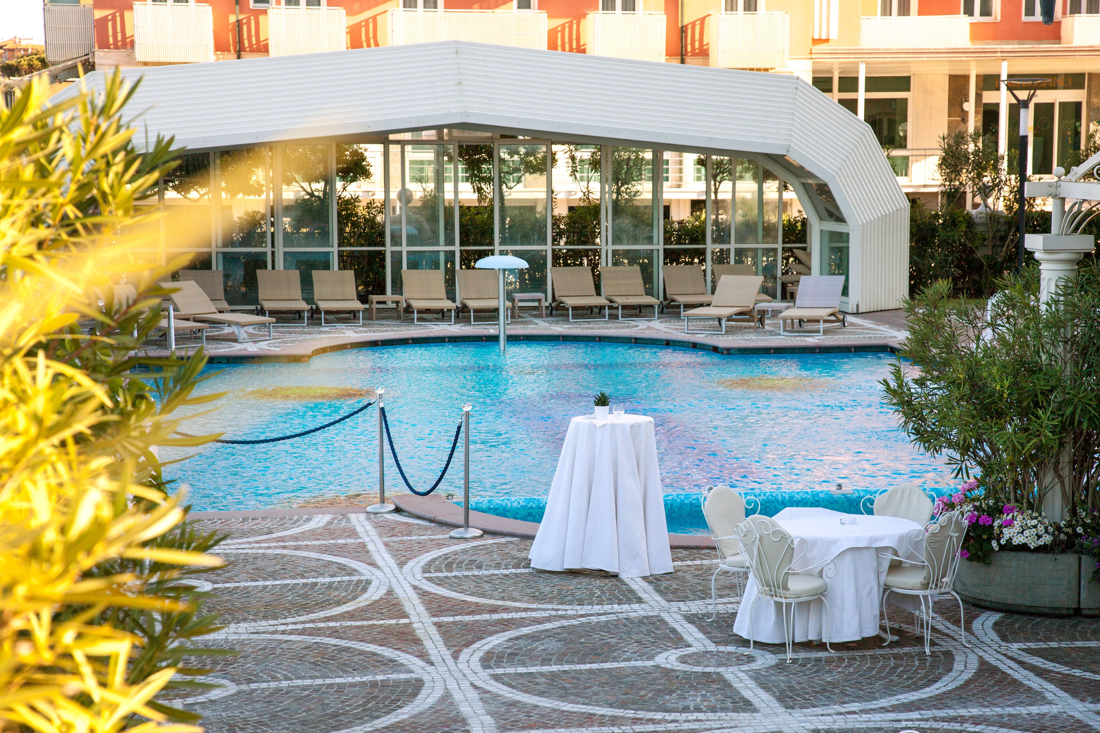 A pool area with lounge chairs, a table, and a covered seating area.