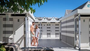 Zona de piscina con varios vestuarios, un paseo cubierto y mobiliario exterior.