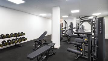 Un gimnasio con bancos, mancuernas y máquinas de pesas.