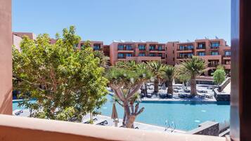 Relax by the pool surrounded by palm trees and modern buildings with comfortable lounge chairs and umbrellas.