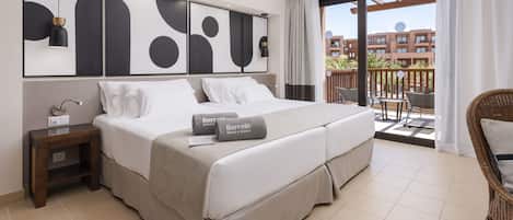 A hotel room with a large bed, a nightstand, a desk lamp, and a view of the outdoor balcony.
