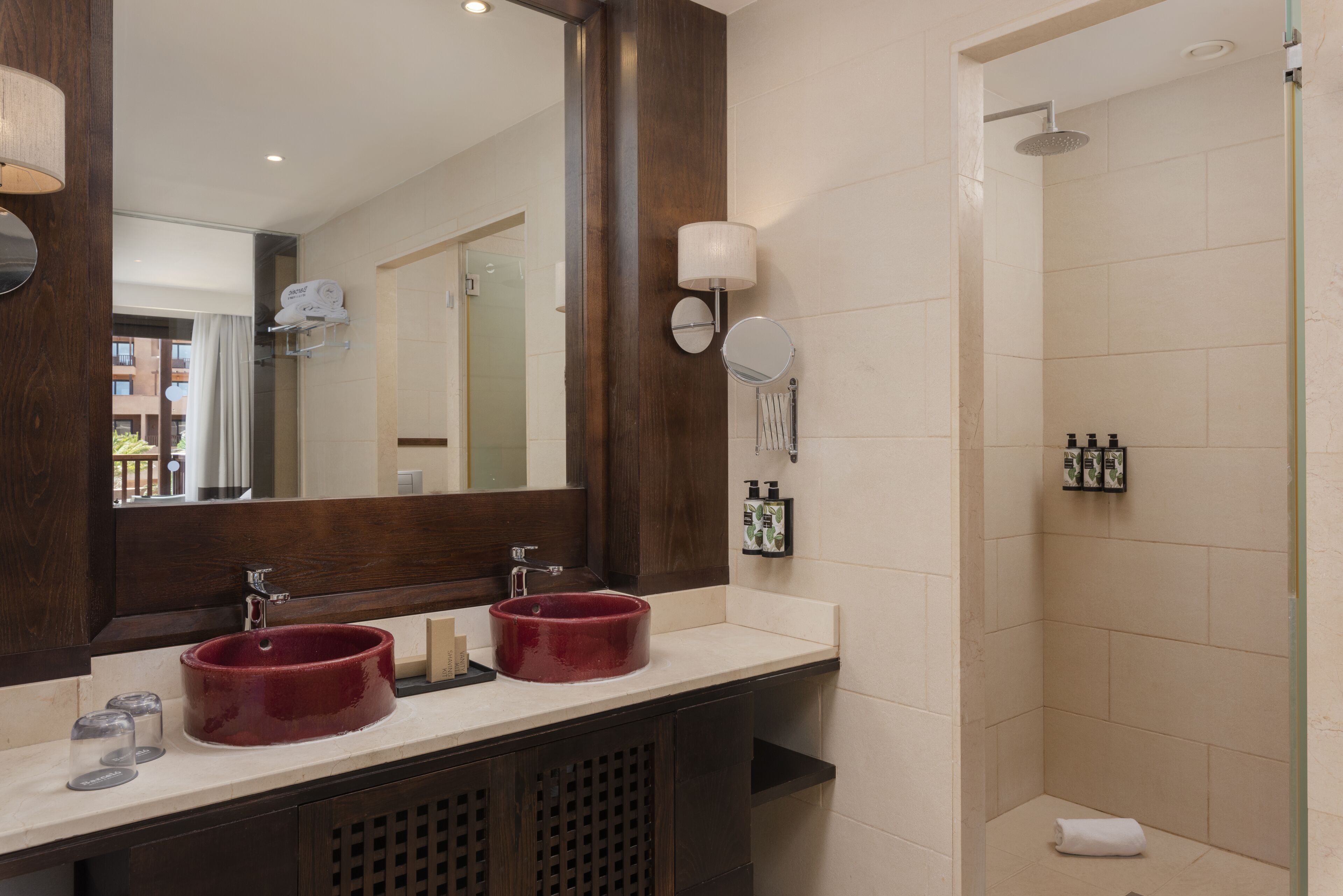 Un baño con dos lavamanos, un espejo grande y una ducha.