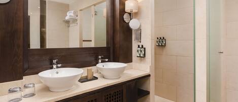 Un baño moderno con dos lavamanos, un espejo grande y una ducha con cerramiento de vidrio.