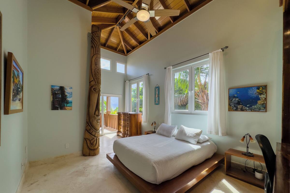 A spacious bedroom with a large bed, a ceiling fan, and a view of the outdoors.