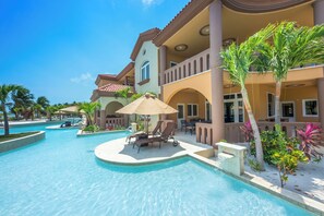 A resort with a swimming pool, lounge chairs, and palm trees.