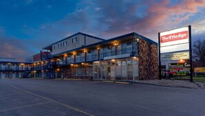 A Thriftdodge building with a large sign, outdoor seating, and a parking lot.