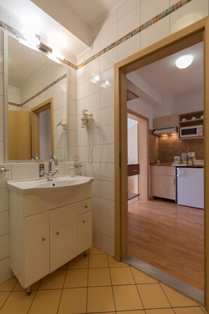 A bathroom with a sink, mirror, and a hairdryer on the wall. - Premium Apartment House (Budapest)