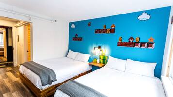 A hotel room with two beds, a blue accent wall, and a small shelf with decorative items.