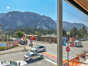 A street view with a mountain in the background, a stop sign, and a rainbow crosswalk.