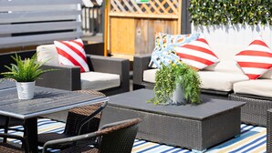 An outdoor seating area with wicker furniture, striped cushions, and potted plants. - Crash Hotel Squamish (Squamish)