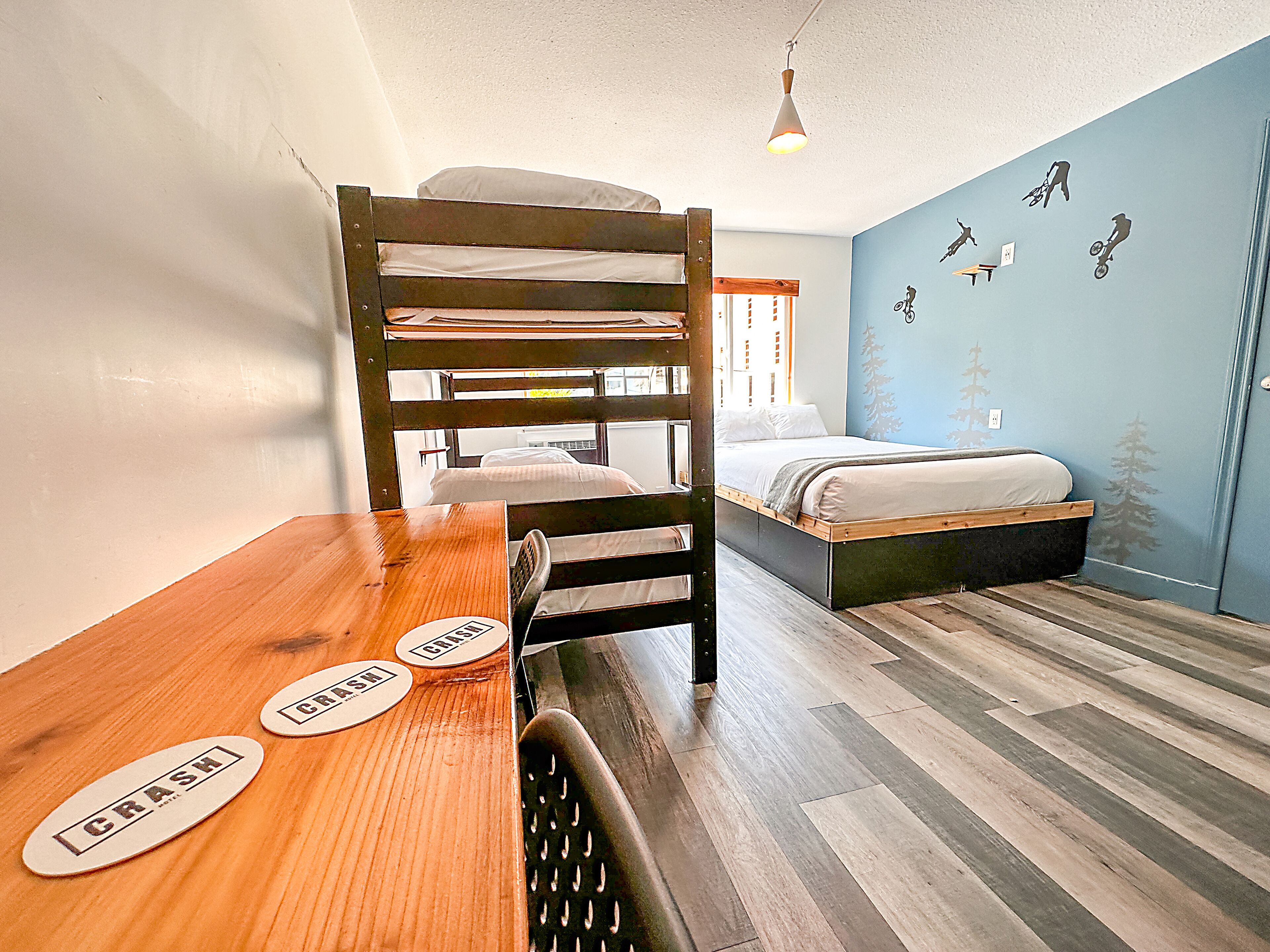 Habitación con literas, una mesa de madera, dos cojines cómodos y una cama con cabecera.