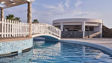 A pool area with a white fence, a bridge, and a building with a stone facade.