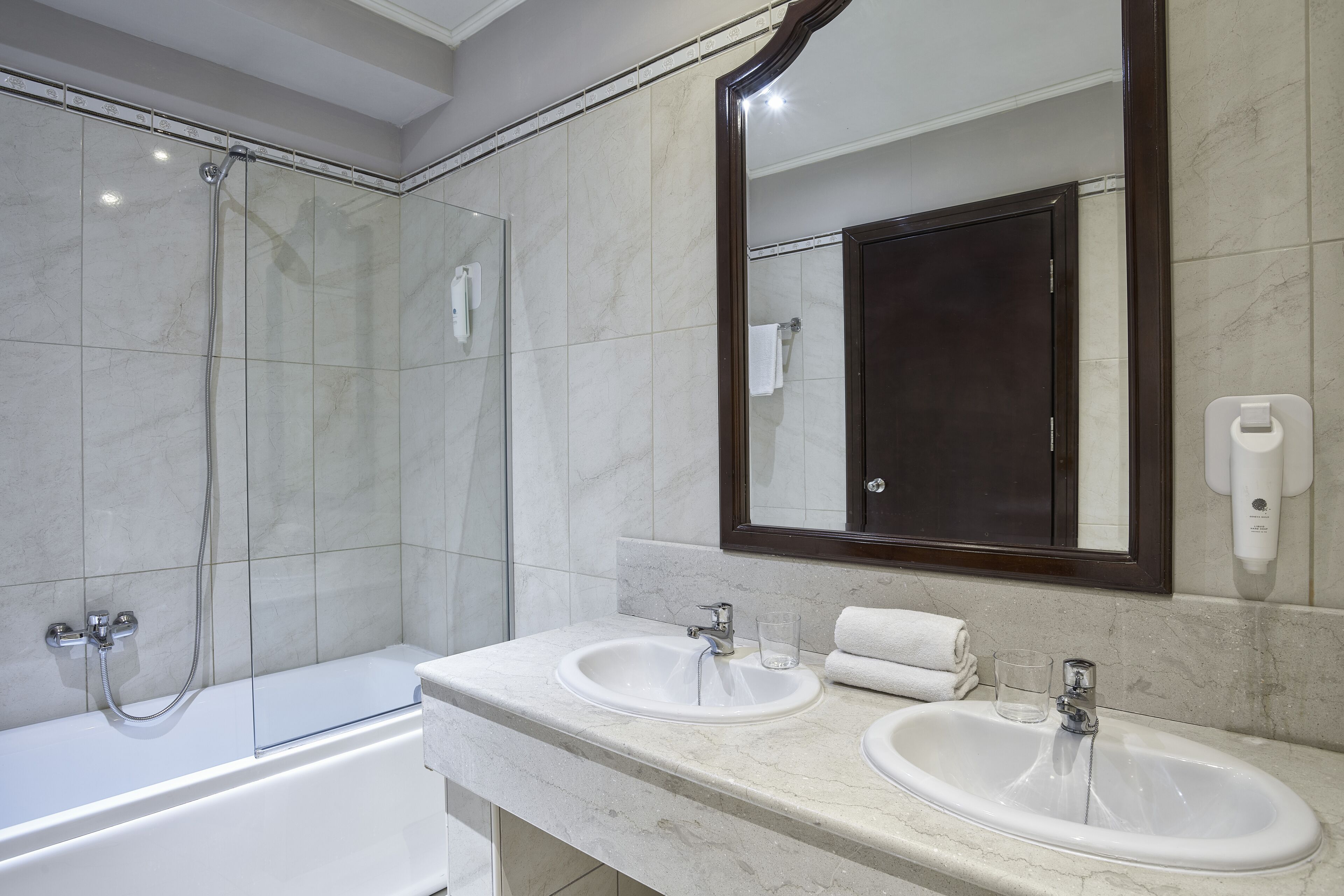 A modern bathroom with a glass-enclosed shower, two sinks, and a large mirror.