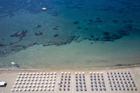 On the beach, sun loungers, beach umbrellas, beach towels. Sandy Beach Resort by Rizos Resorts
