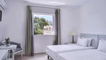 A hotel room with two beds, a desk, a chair, and a window with curtains.