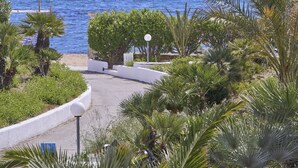 Vista costera con cielo despejado, una playa arenosa y exuberante vegetación.