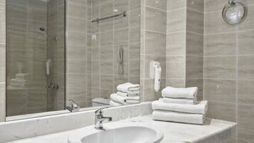 A bathroom with a large mirror, a sink, a glass shower enclosure, and a towel rack.