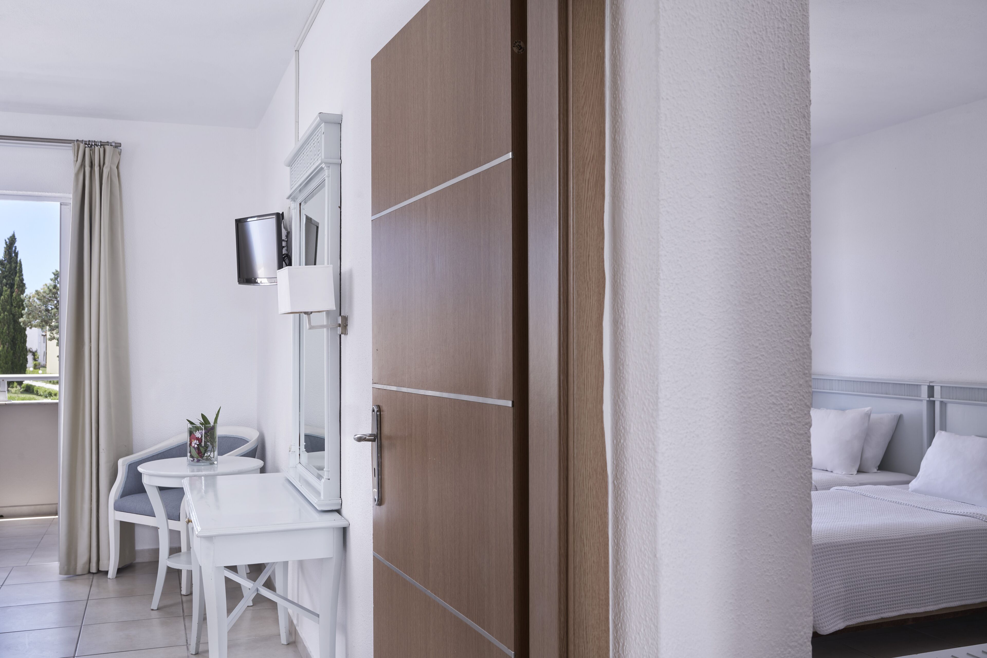 Habitación de hotel con cama, escritorio y silla. Cuenta con ventana con cortinas, televisor de pantalla plana en la pared y vistas al exterior.
