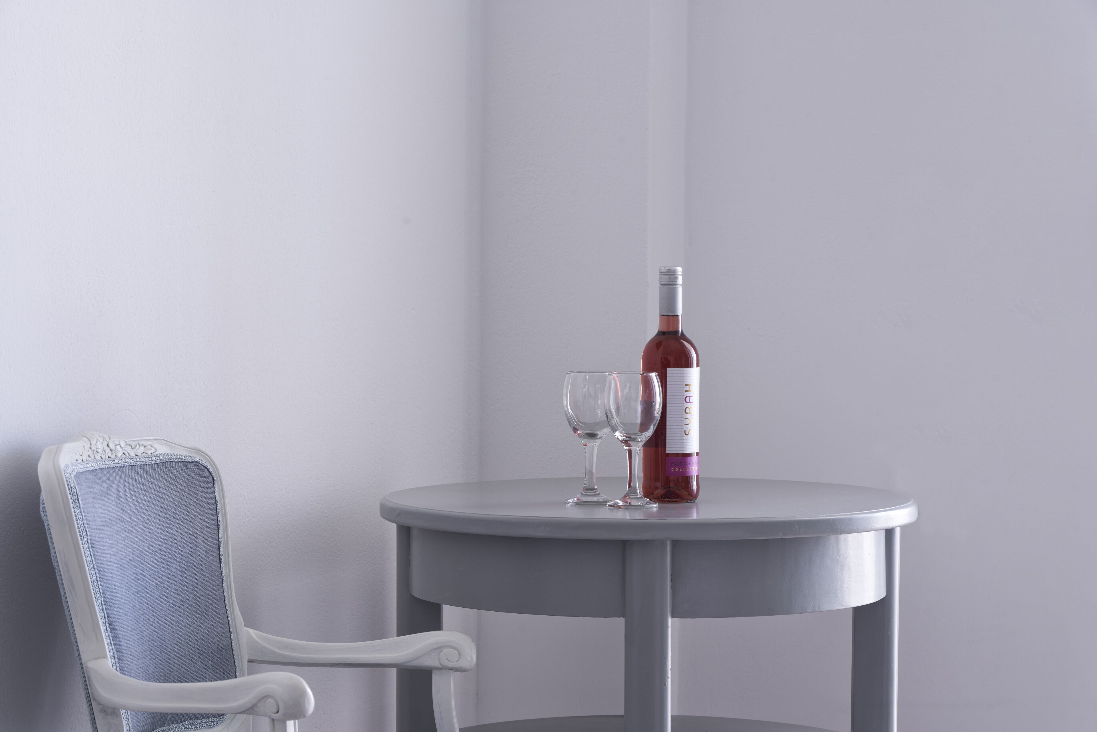 A round table with a bottle of wine and two glasses on it.
