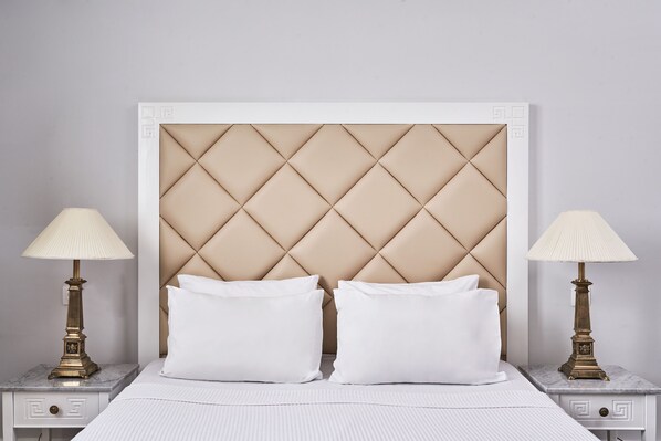 A bed with a tufted headboard, two bedside tables with lamps, and a white bedspread.