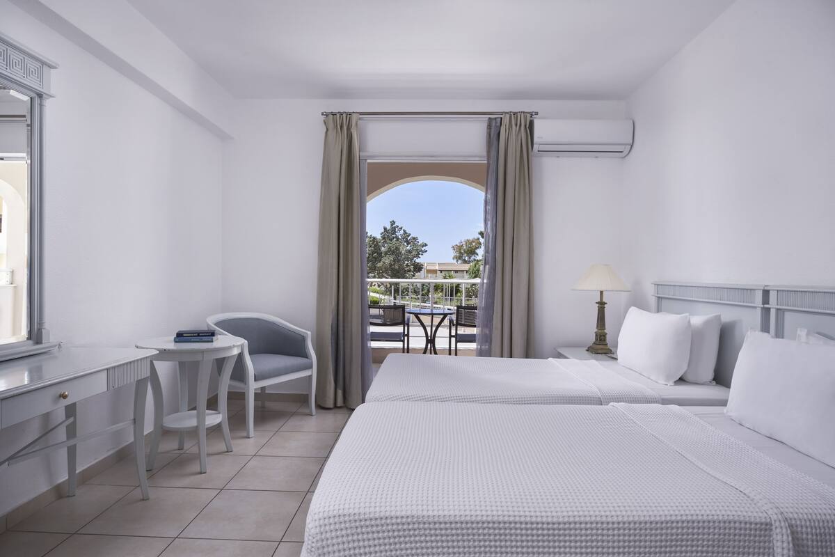 Une chambre d’hôtel avec deux lits, un bureau, une chaise et une vue sur l’espace extérieur.
