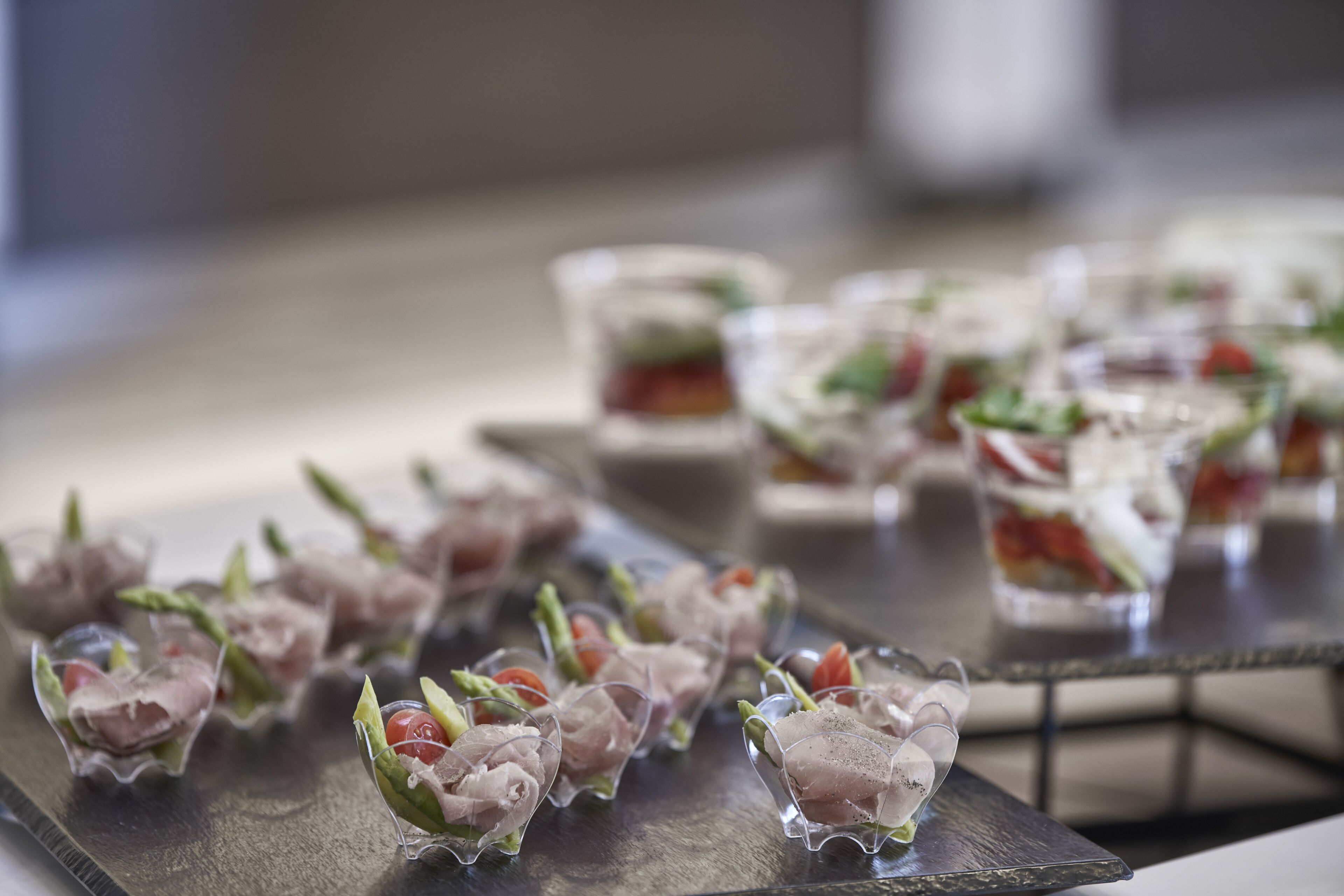 A tray of appetizers with various garnishes and a glass of salad.