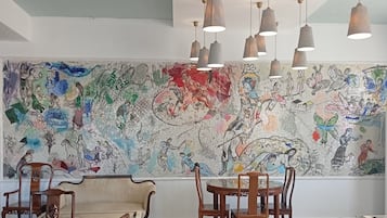 A dining area with a mural, wooden furniture, and pendant lighting.