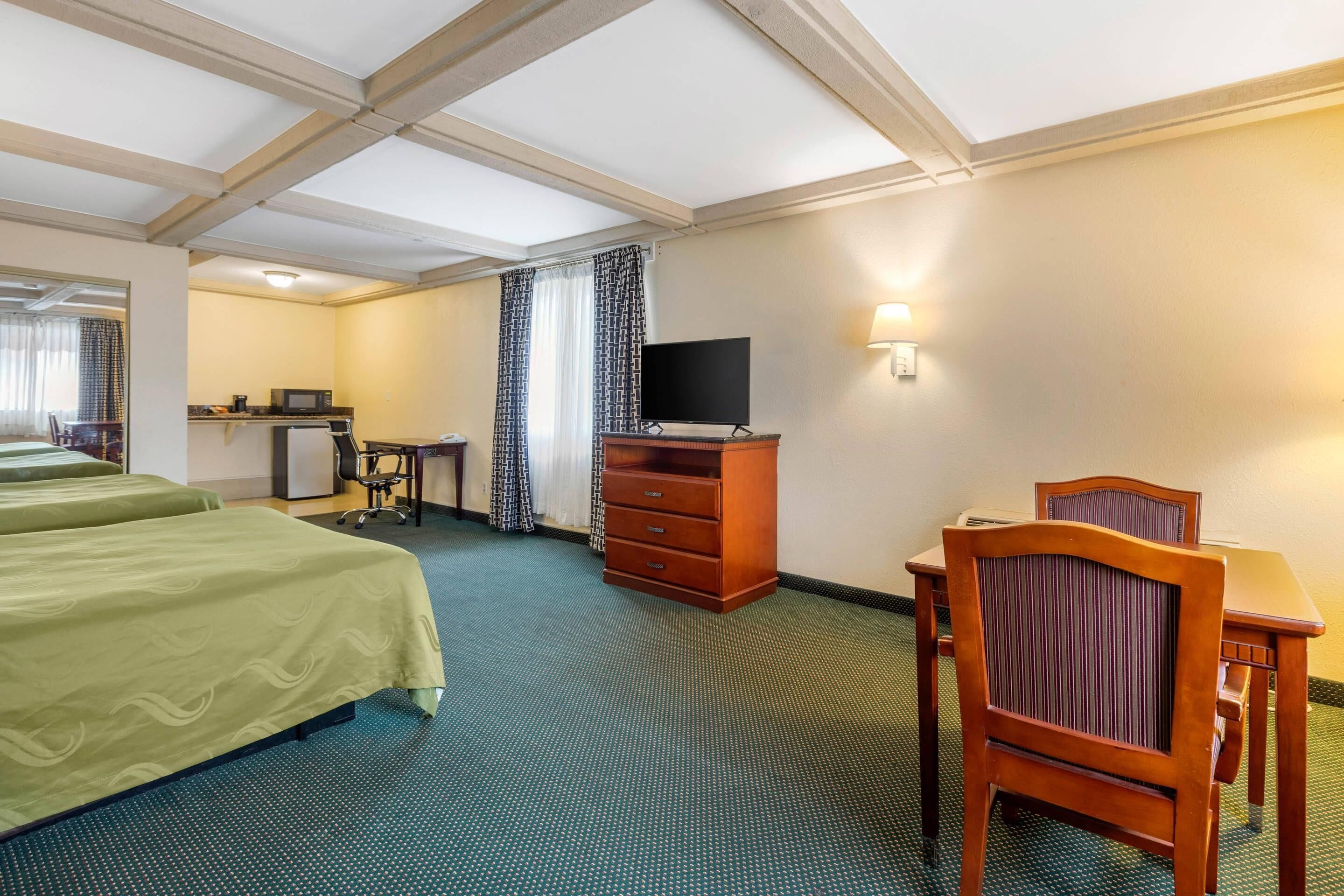 Hotellihuone, jossa on kaksi sänkyä, työpöytä, televisio ja tuoli.