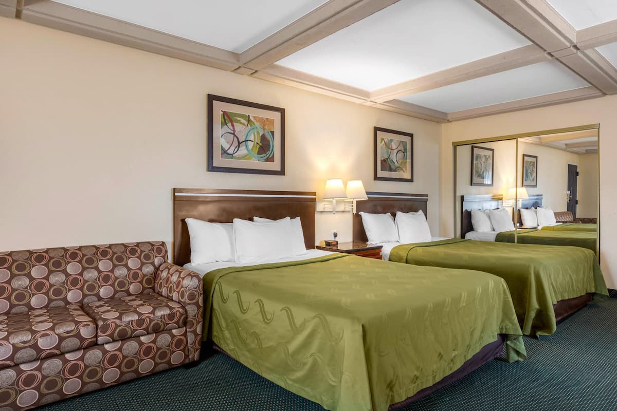 Una habitación de hotel con dos camas, un sofá y obras de arte en las paredes.