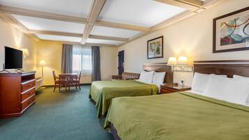 A hotel room with two beds, a desk with a chair, a TV, and a window with curtains.
