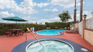 Un espace piscine comprenant un jacuzzi, des chaises longues et des tables de pique-nique.