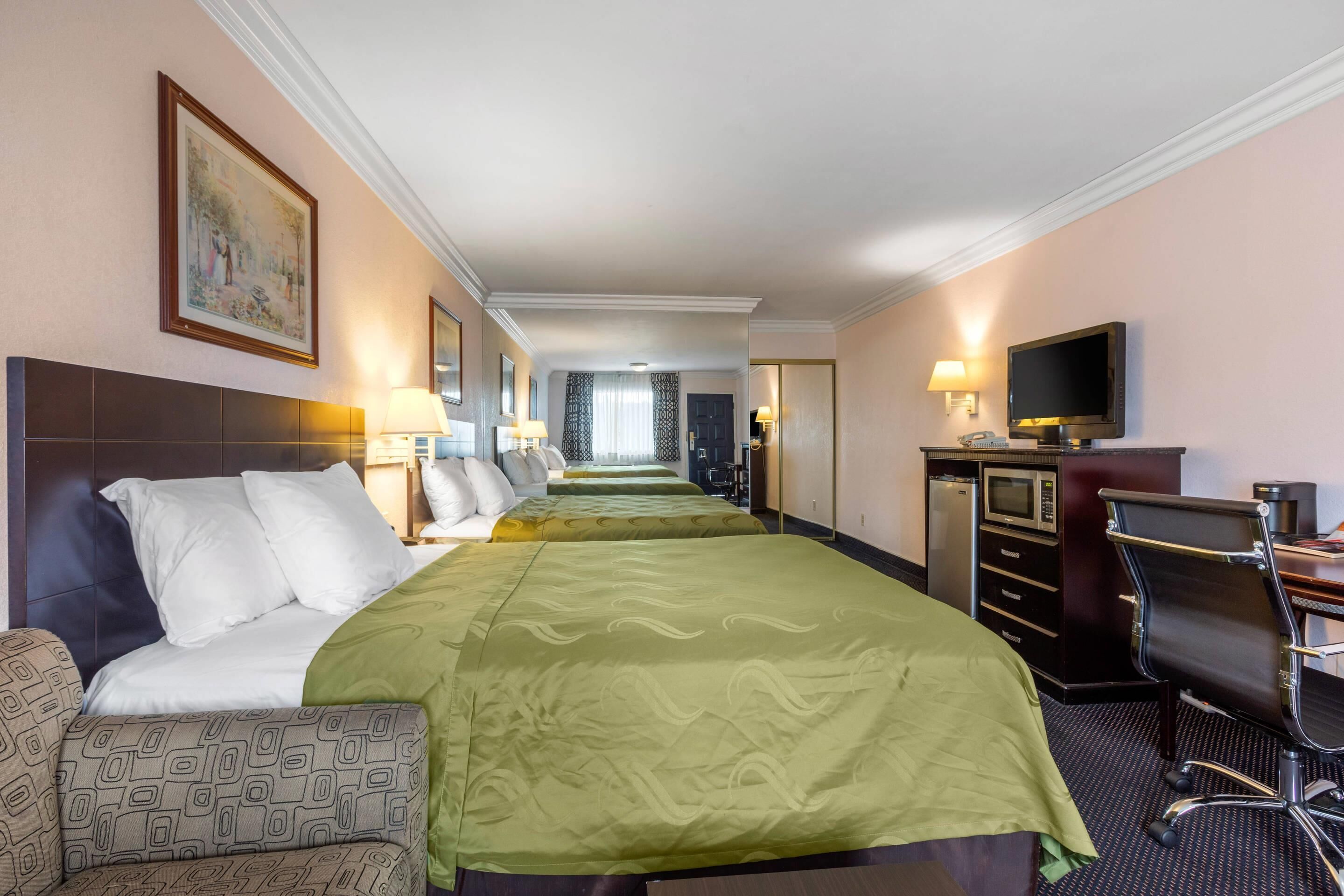 Habitació d'hotel amb un llit gran, una escriptori, una cadira, una televisió i un minibàr.