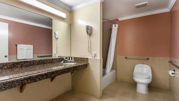 Une salle de bain avec un comptoir en granit, des toilettes blanches, une douche avec un rideau, un sèche-mains et un porte-serviettes.