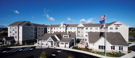 A multi-story hotel with a central courtyard, flagpoles, and a parking lot.