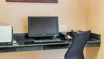 Un escritorio con una computadora, una silla y un cuadro en la pared.