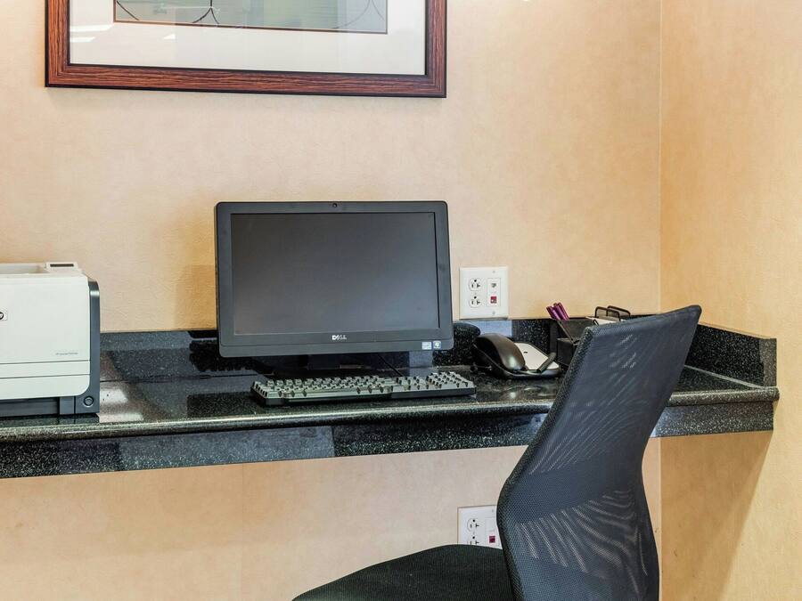 Un escritorio con una computadora, una silla y un cuadro en la pared.