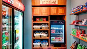 A refrigerated display case with various snacks and beverages, a wooden cabinet with shelves of packaged goods, and a Coca-Cola sign above the case.